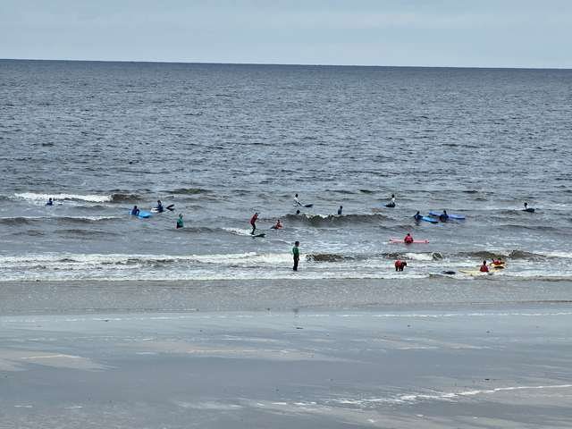 lots of beginner surfers in the shallows catching small waves